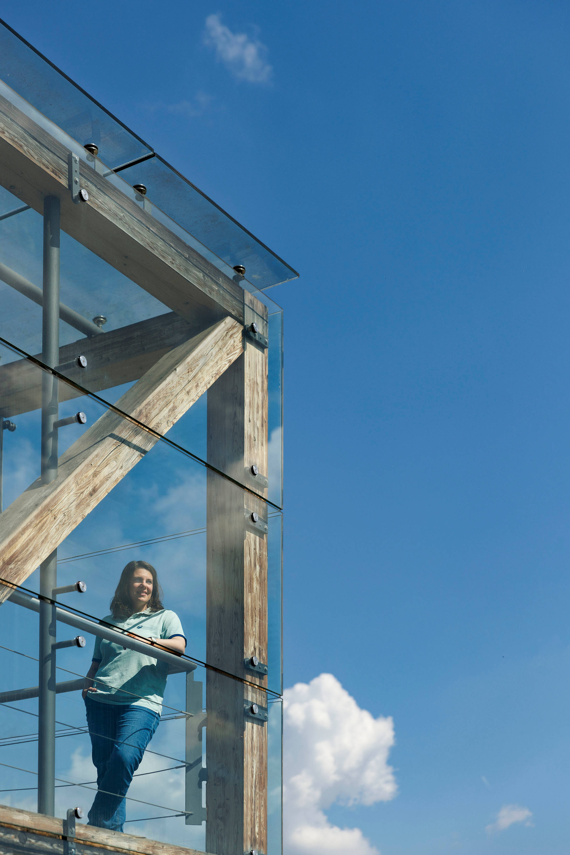 Frau lehnt in glasigem Treppenhaus an Geländer