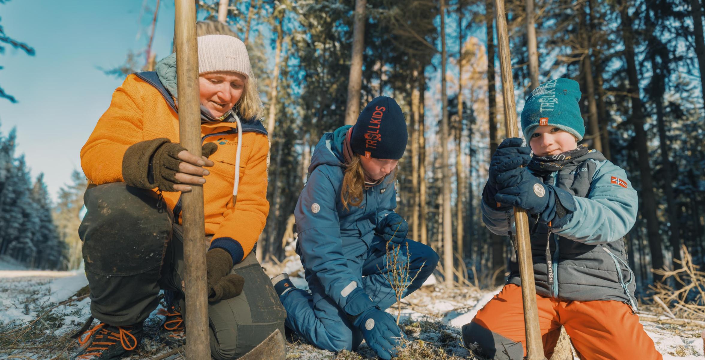Försterin pflanzt Baum mit Kind