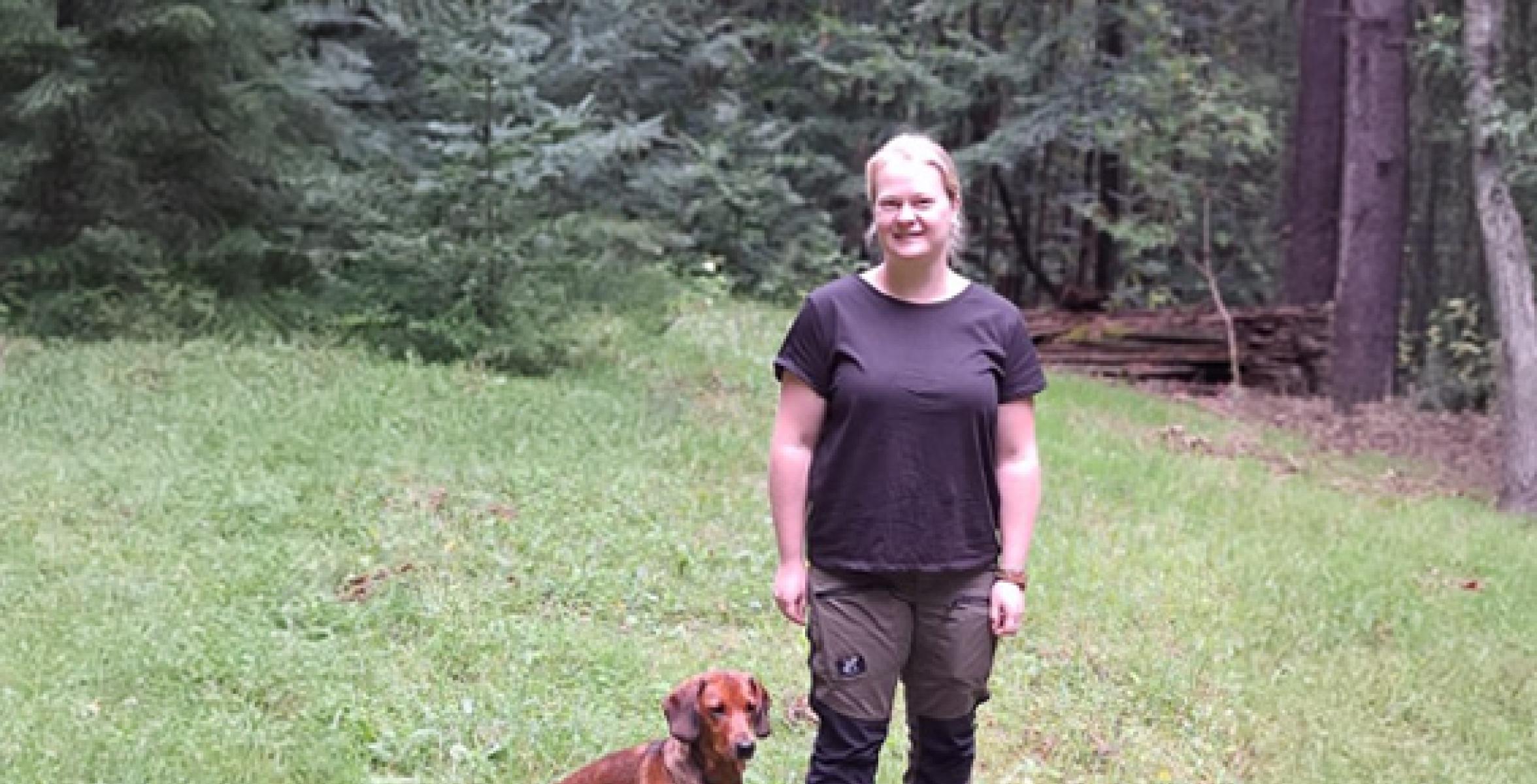 Revierleiterin mit Hund vor einem Wald
