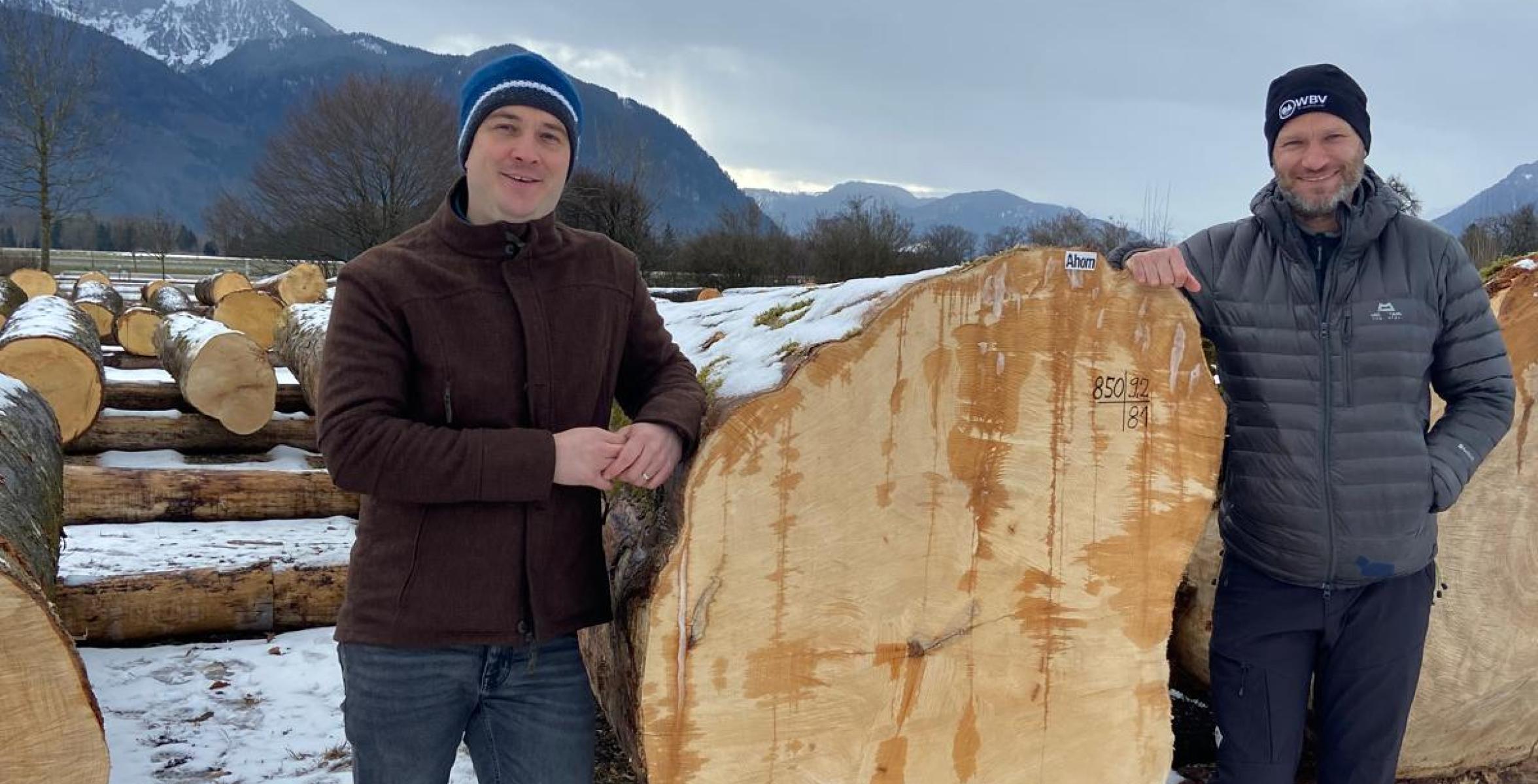 2 Männer vor einem Holzstamm
