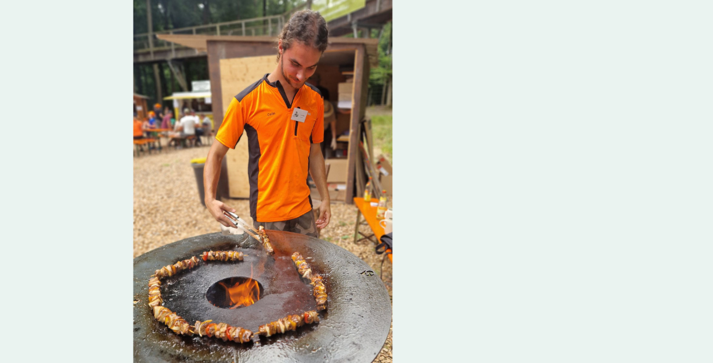 Ein Forstwirt grillt Wildfleisch auf einem runden Grill