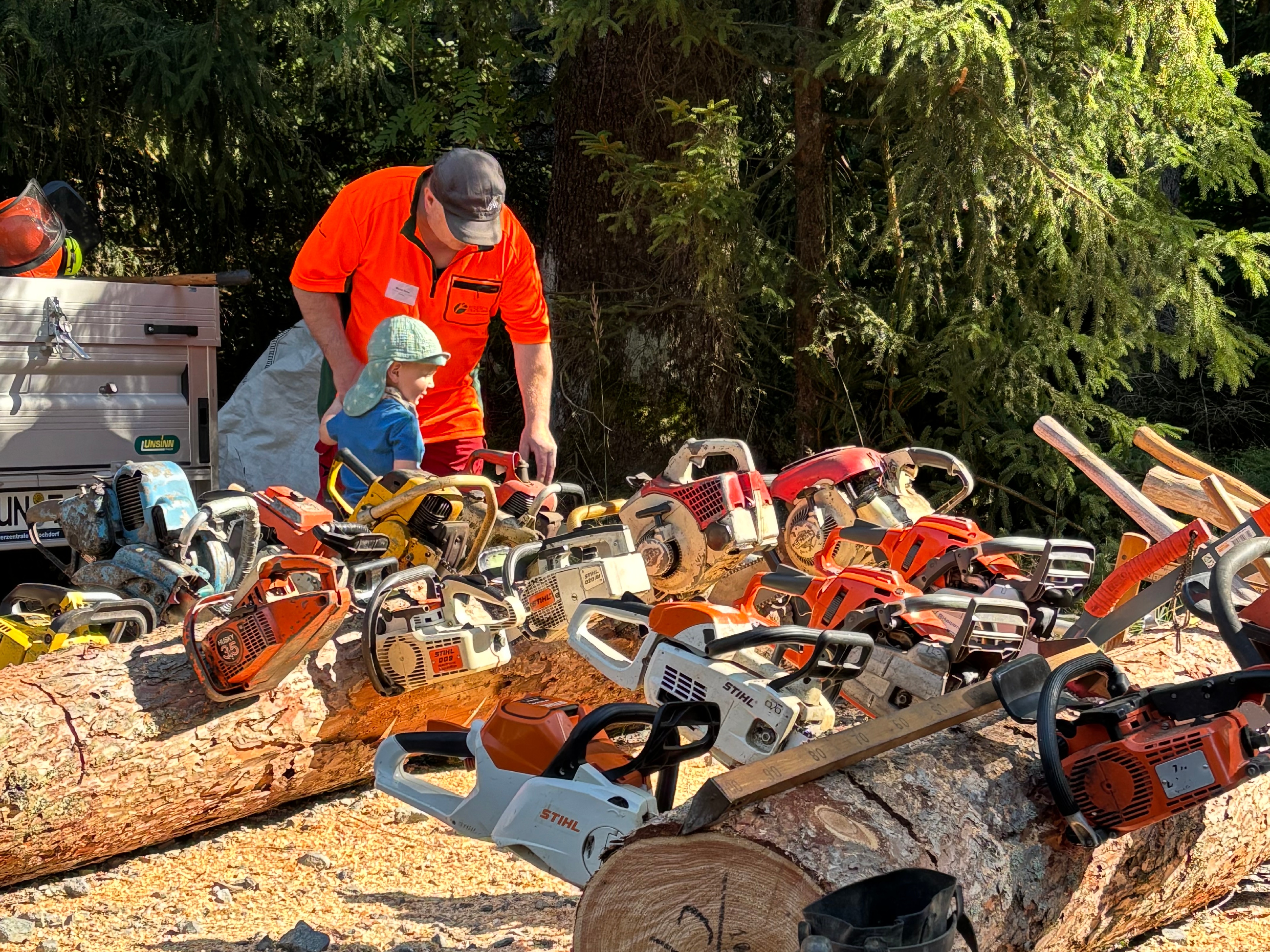 Kleines Kind mit Mann bei Motorsägen